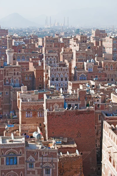 Yemen, Medio Oriente: veduta aerea dello skyline della capitale Sana'a, patrimonio mondiale dell'Unesco, con la Moschea di Al Saleh nella nebbia e i palazzi unici e le case a torre in pietra decorate con motivi geometrici di mattoni cotti e gesso bianco — Foto Stock