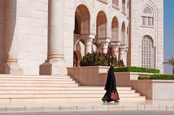 Yemen, Middle East: a veiled yemeni woman walking in front of the Al Saleh Mosque, the largest and most modern mosque in Sana'a, the capital of Yemen, Unesco world heritage site — Stock Photo, Image