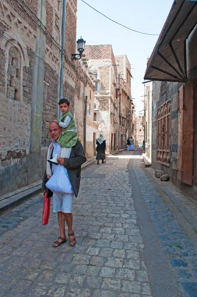 Iêmen, Oriente Médio: um homem iemenita com o filho em seus ombros nas ruelas da cidade velha de Saná, capital do país, a cidade continuamente habitada e povoada mais antiga do mundo, Patrimônio Mundial da Unesco — Fotografia de Stock