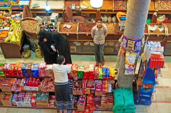 Yemen, Middle East: yemeni boys and veiled women in the grocery shop of the covered market in Suq al-Milh, the salt market of the old city of Sana'a — Stock Photo, Image