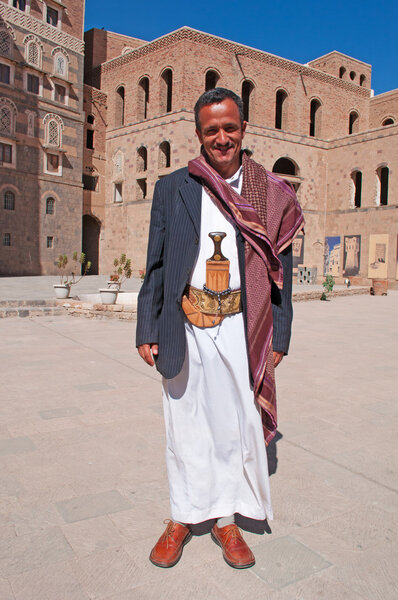 Yemen, Middle East: a yemeni man wearing dishdasha (the traditional yemeni dress) and Janbiya (the yemeni dagger with a short curved blade) at the entrance of the National Museum of Yemen in the old town of Sana'a