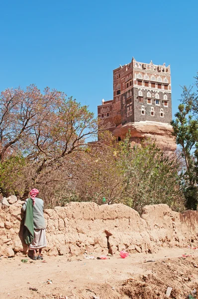 Yemen, Middle East: a yemeni man looking at Dar al-Hajar (Stone House), Rock Palace in Wadi Dhahr valley, a royal palace on top of a rock built as a summer retreat near the capital city of Sana\'a, one of the most iconic yemeni buildings