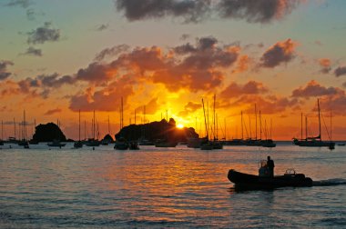 Saint Barthelemy (St Barth, St. Barths veya St. Barts): bir adam bir sandal ve Yelkenli ve yatlar ile nefes kesen bir gün batımı Gustavia limanda palamarla 