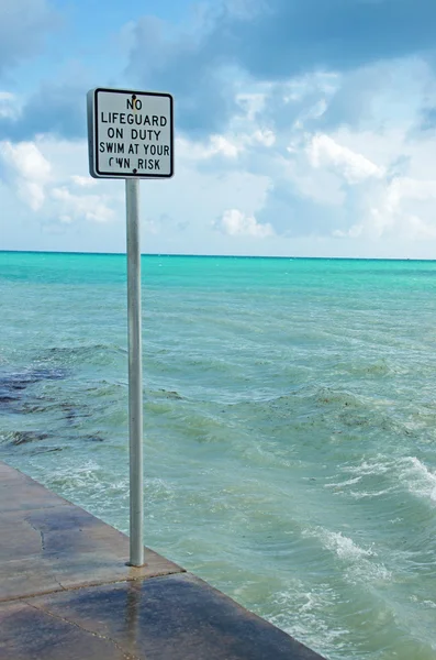 Key West: the pier and the sign of no lifeguard on duty at Higgs Beach, the two mile long strip of sandy beach along the Key West coastline