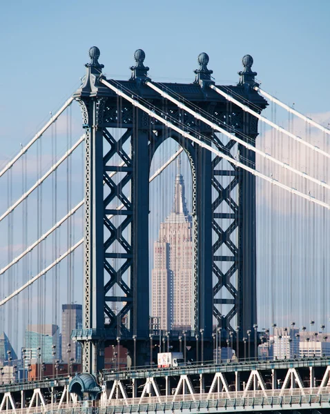 Nueva York, Estados Unidos de América: el emblemático Empire State Building, un rascacielos de 102 pisos de estilo Art Deco en Midtown Manhattan, visto a través del puente Manhattan, un puente colgante que cruza el East River — Foto de Stock