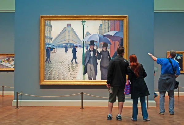 Chicago: Leute, die sich die berühmte Straße von Paris ansehen; Regentag, ein Ölgemälde des Künstlers gustave caillebotte aus dem Jahr 1877 in einem Saal des Kunstinstituts von Chicago — Stockfoto