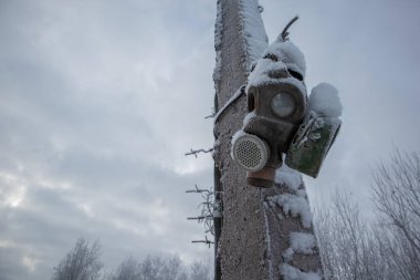Kışın direğe asılı eski gaz maskesi. karla kaplı.