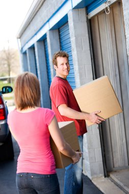 Caucasian man and woman with various props at a typical commercial storage unit. clipart