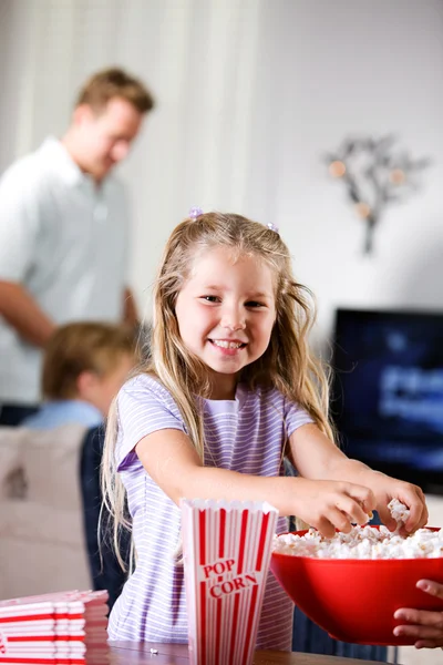 Familie: Lächelndes junges Mädchen hilft mit Popcorn Stockbild