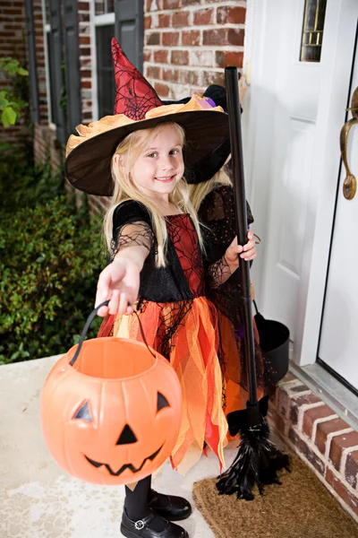 Halloween: dziewczyna czarownic na ganku dzwoni dzwonek do drzwi — Zdjęcie stockowe