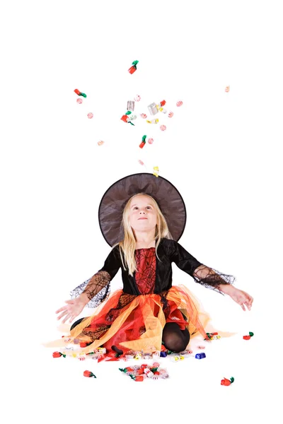 万圣节： 小女巫把糖果扔在空气中 图库照片