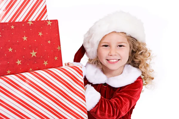 Рождество: Santa Girl Peeks Around Big Stack Of Christmas Presen — стоковое фото