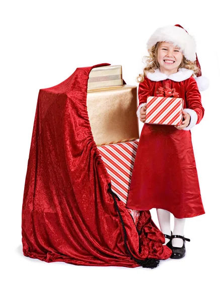 Weihnachten: Kleines Mädchen steht neben Sack voller Weihnachtsgeschenke — Stockfoto