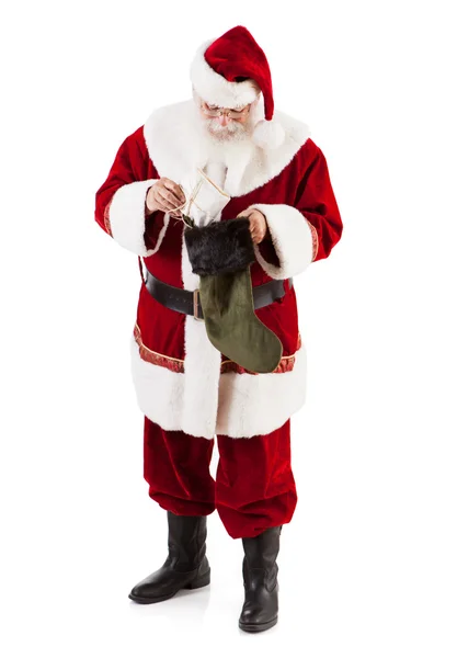 Papá Noel poniendo regalo en la media de Navidad — Foto de Stock