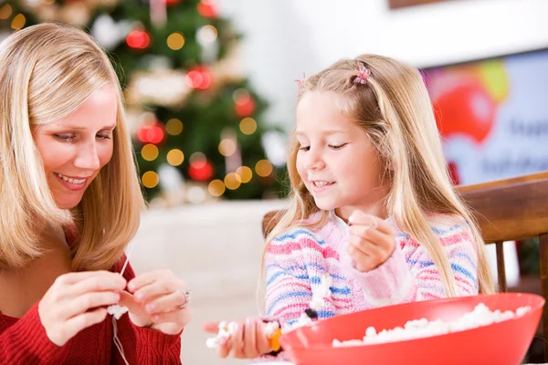 Navidad: Chica y madre trabajando juntas para hacer palomitas de maíz Garl — Foto de Stock