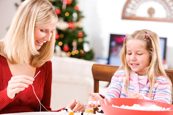 Рождество: мать и ребенок делают праздник гирлянду из попкорна — стоковое фото