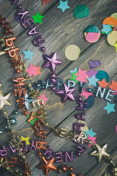 NYE: Confetti festa e colares Feliz Ano Novo em madeira Backg — Fotografia de Stock