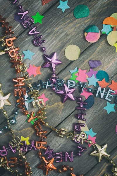 NYE: Confetti fiesta y feliz año nuevo collares en respaldo de madera — Foto de Stock