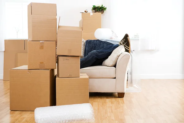 Mover-se: homem faz uma pausa no sofá da embalagem — Fotografia de Stock