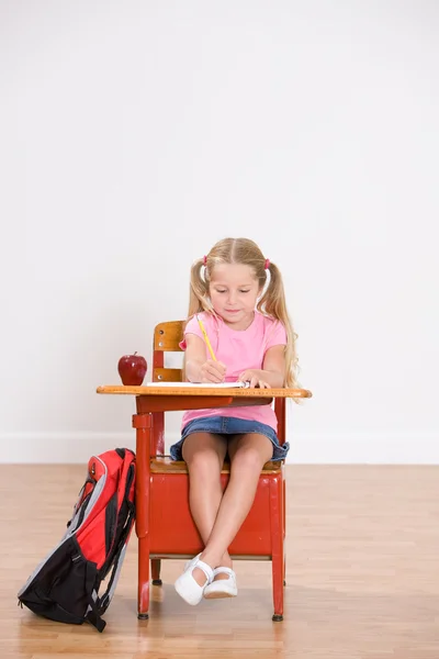 Escuela: Estudiante niña se sienta en el escritorio haciendo la tarea — Foto de Stock