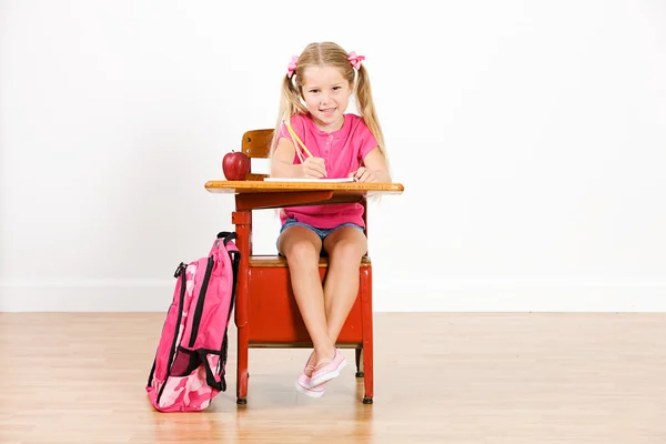 Estudiante: Chica sonriente en el escritorio escribiendo en el cuaderno — Foto de Stock