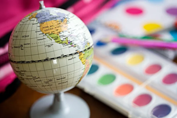 Edukacja: Ziemia świecie siedzi wśród przyborów szkolnych — Zdjęcie stockowe