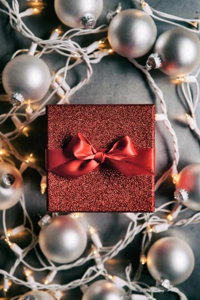 Día de fiesta: Regalo de brillo rojo entre las luces de Navidad — Foto de Stock