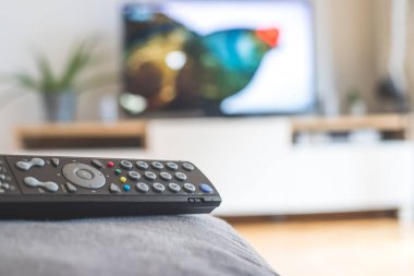 Ön planda TV uzaktan kumandası, bulanık arkaplanda TV. Akıyor.