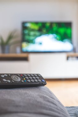 Ön planda TV uzaktan kumandası, bulanık arkaplanda TV. Akıyor.