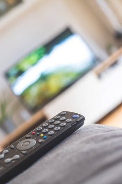 Ön planda TV uzaktan kumandası, bulanık arkaplanda TV. Akıyor.