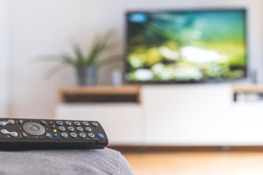 Ön planda TV uzaktan kumandası, bulanık arkaplanda TV. Akıyor.