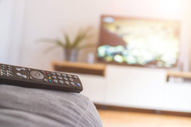Ön planda TV uzaktan kumandası, bulanık arkaplanda TV. Akıyor.
