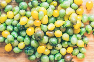 Kokteyl domateslerini ahşap tabakta yakın, sarı ve yeşil