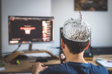 Young man is wearing aluminum cap, conspiracy theory concept clipart