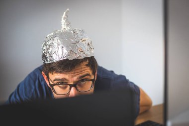 Genç adam alüminyum şapka giyiyor, komplo teorisi konsepti.