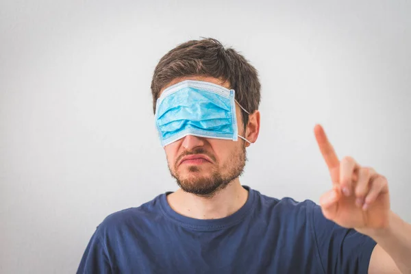 Young angry man waring face mask is gesturing angry. Conspiracy theory concept.