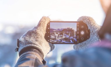 Genç turist Salzburg 'un fotoğrafını çekiyor. Akıllı telefonuyla, kış zamanı.