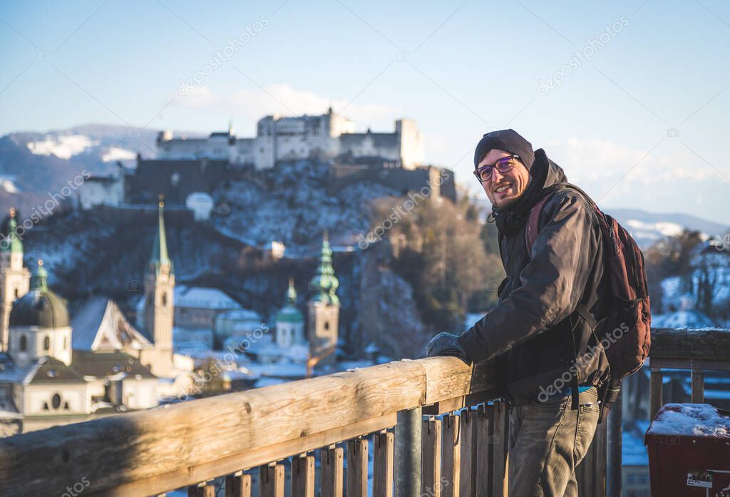 Young man in winter jacket is enjoying the view over Salzburg, historic center 