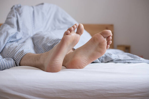 Закрыть обнаженные женские взрослые ноги, спящие в постели, утром