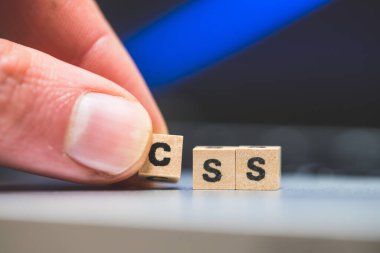 Üzerinde CSS harfleri olan tahta küpler dizüstü bilgisayarda yatıyor..