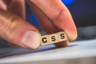 Üzerinde CSS harfleri olan tahta küpler dizüstü bilgisayarda yatıyor..