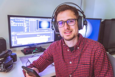 Kurgu odasında, monitörlerde ve arka planda genç beyaz video editörünü kapat