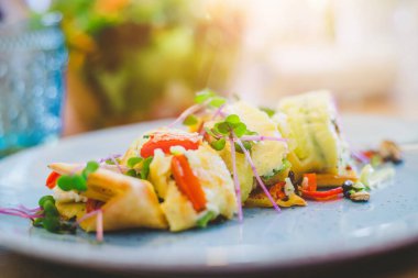 Yumurtalı omleti taze sebzelerle kapat. Beyaz seramik tabağa yerleştirilmiş.