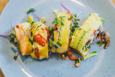 Yumurtalı omleti taze sebzelerle kapat. Beyaz seramik tabağa yerleştirilmiş.