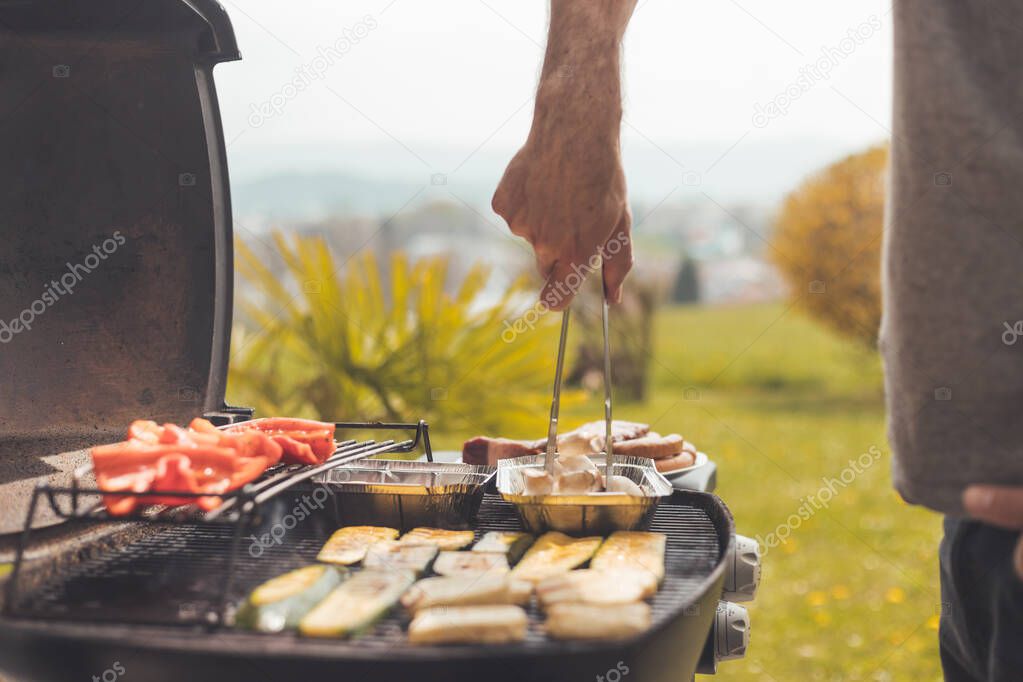 Close up of cheese and vegetables on gas grill. Summer time, outdoors.