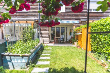 Yükseltilmiş yatağı ve verandası olan küçük yeşil bir bahçe, yaz zamanı. 