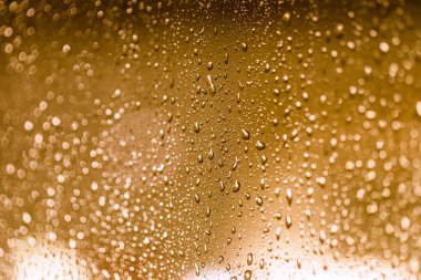 Yağmurlu gecelerde pencereye düşen yağmur damlalarını kapat, sıcak ışıklar