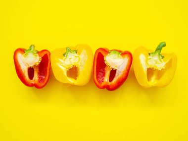 Kırmızı ve sarı dolma biberler yarısından dilimlenmiş ve sarı arka planda izole edilmiş tohumlar yukarıdan görünüyor - deri yüzme kavramı