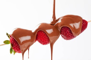 Erimiş sütlü çikolatalı çilekli şiş. Stüdyoya beyaz bir arka planla izole edilmiş olarak dökülüyor.