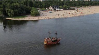 Turistik vintage yelkenli gemi güneşli havada sakin sularda yelken açıyor: Uçan İHA 'dan güzel 4K panoramik hava klibi, sinematik yaz tatili manzarası
